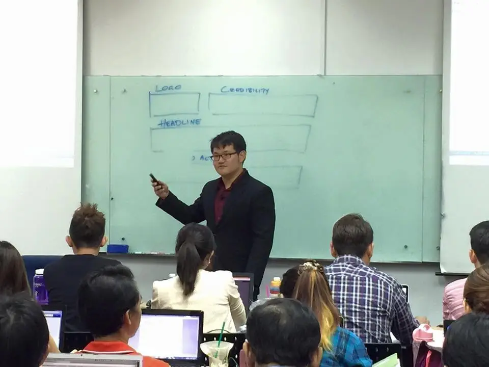 Jonathan Seet teaching sales page structure at a whiteboard during an early Maneuver Marketing workshop